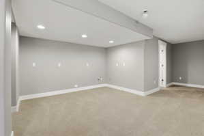 Empty room with light colored carpet and recessed lighting