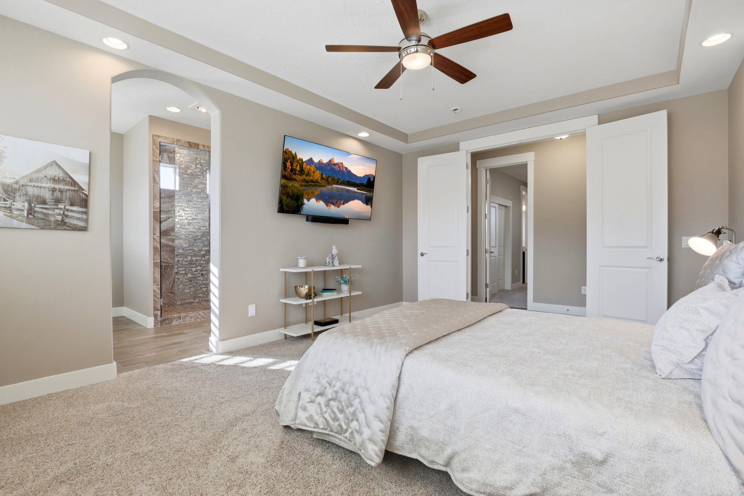 Bedroom featuring recessed lighting, light carpet, a ceiling fan, ensuite bathroom, and arched walkways