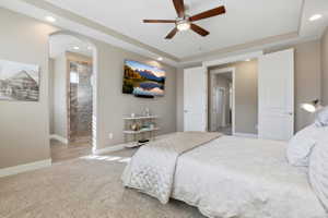 Bedroom featuring recessed lighting, light carpet, a ceiling fan, ensuite bathroom, and arched walkways