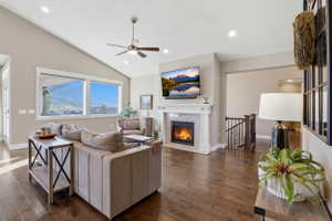 Living room featuring a ceiling fan, dark wood finished floors, a tiled fireplace, lofted ceiling, and recessed lighting
