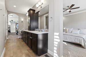 Full bathroom featuring connected bathroom, double vanity, a ceiling fan, wood finish floors, and tasteful backsplash