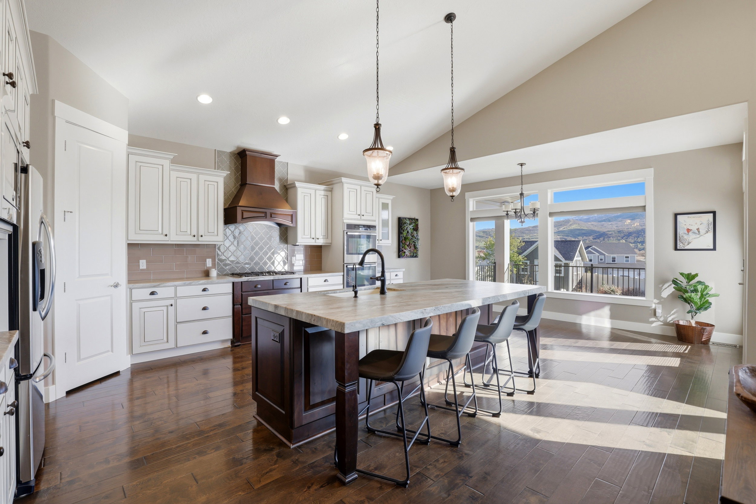 Kitchen with a breakfast bar, a center island with sink, two tone cabinetry, dark wood-style floors, and decorative backsplash