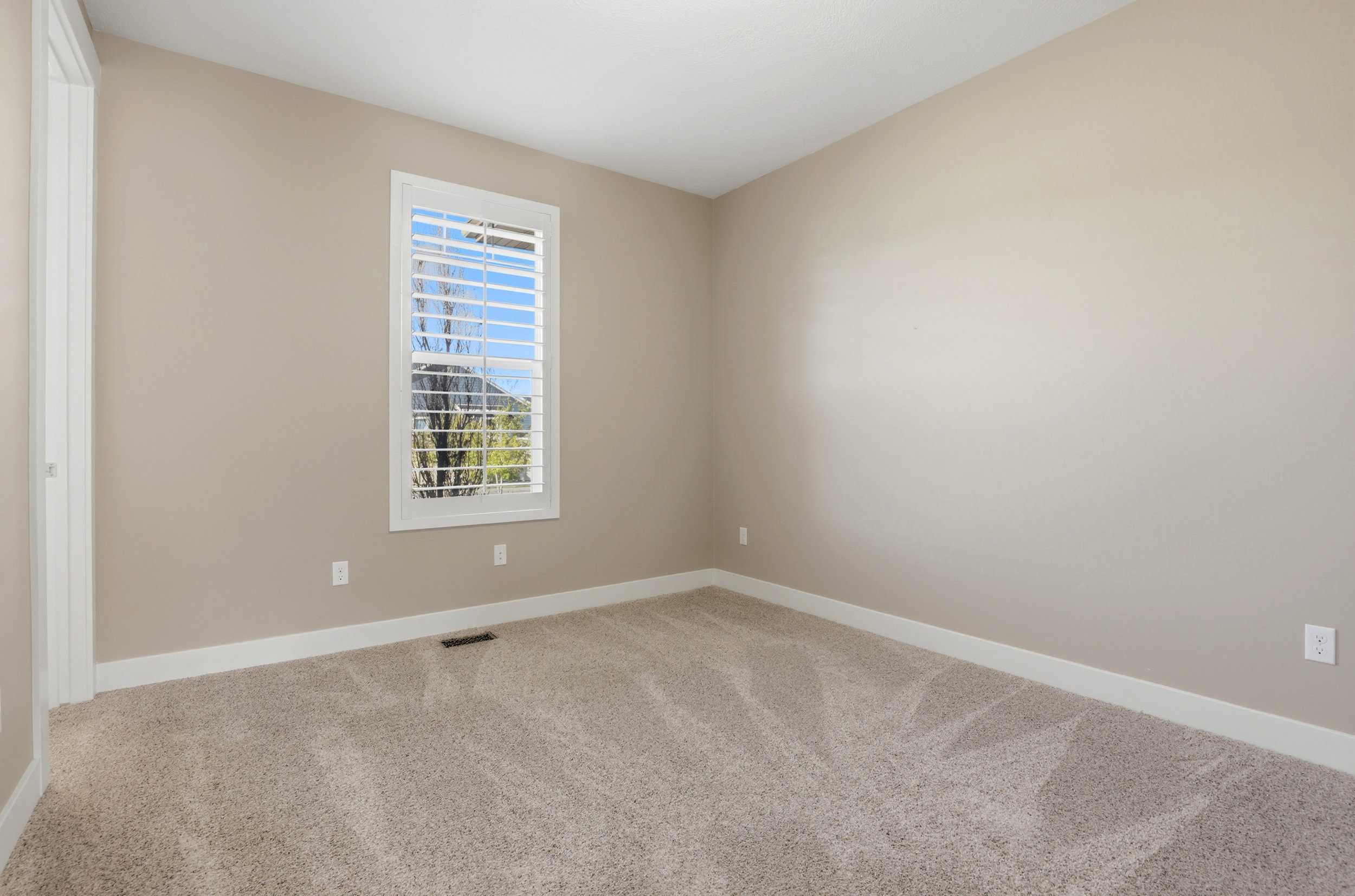 Empty room with light carpet and baseboards