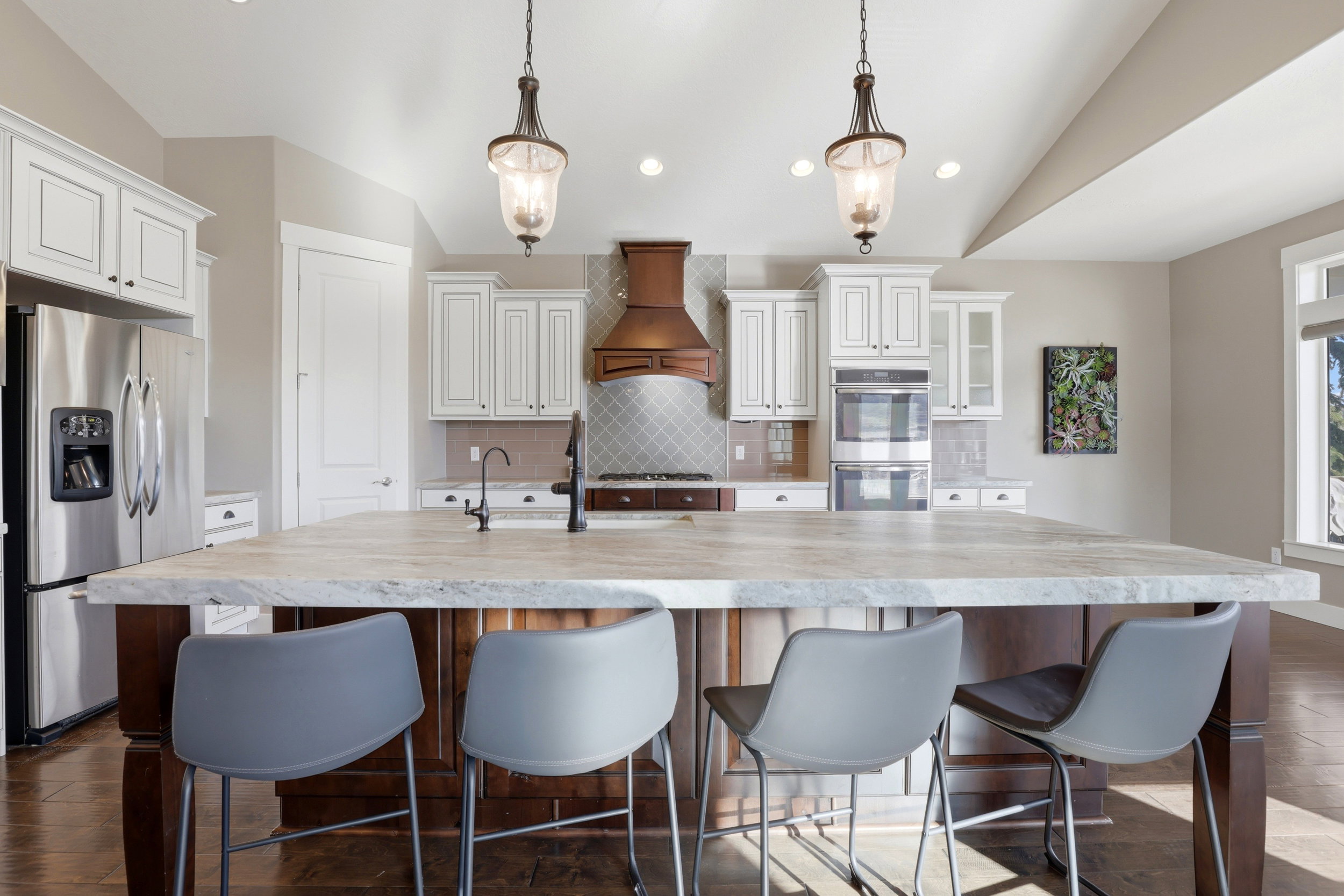 Kitchen featuring dark wood-type flooring, stainless steel appliances, a breakfast bar area, a large island, and vaulted ceiling