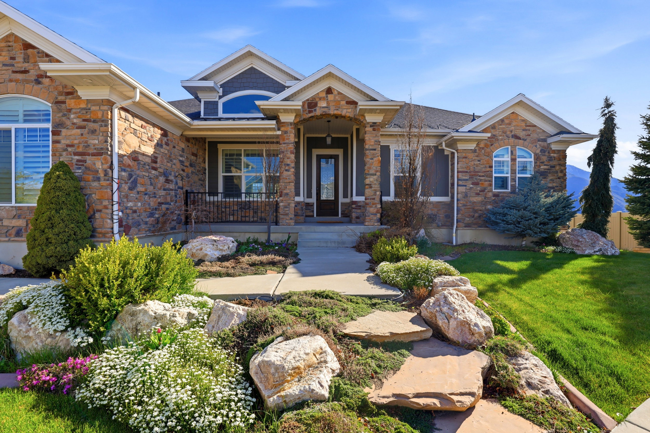 Craftsman house featuring a porch, stone siding, and a front lawn