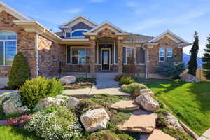Craftsman house featuring a porch, stone siding, and a front lawn