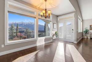 Foyer entrance with a mountain view, dark wood-style floors, suspended lighting, and vaulted ceiling