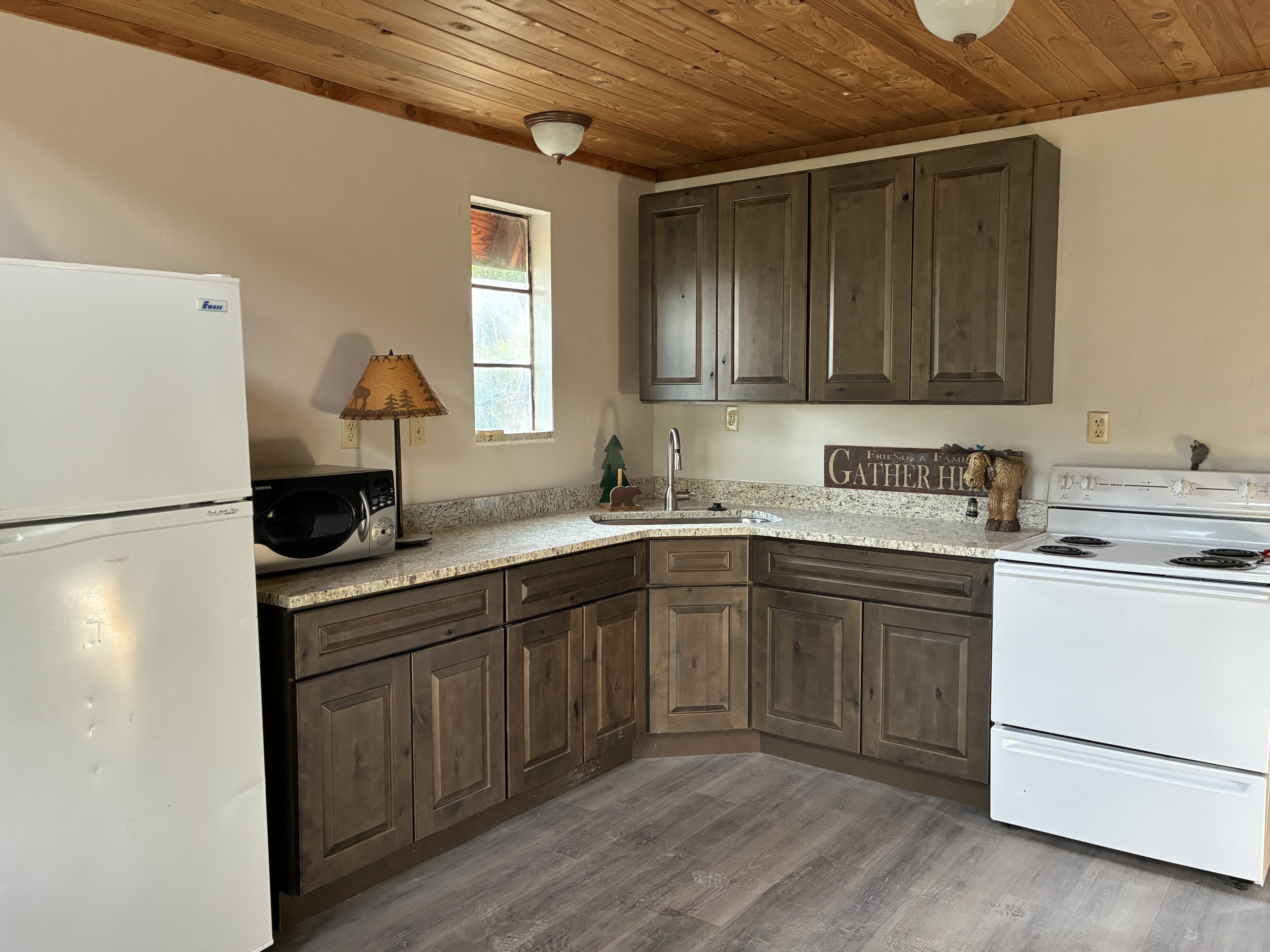 New kitchen with dark wood finish cabinetry, wood-style floors, wooden ceiling, and granite counters.