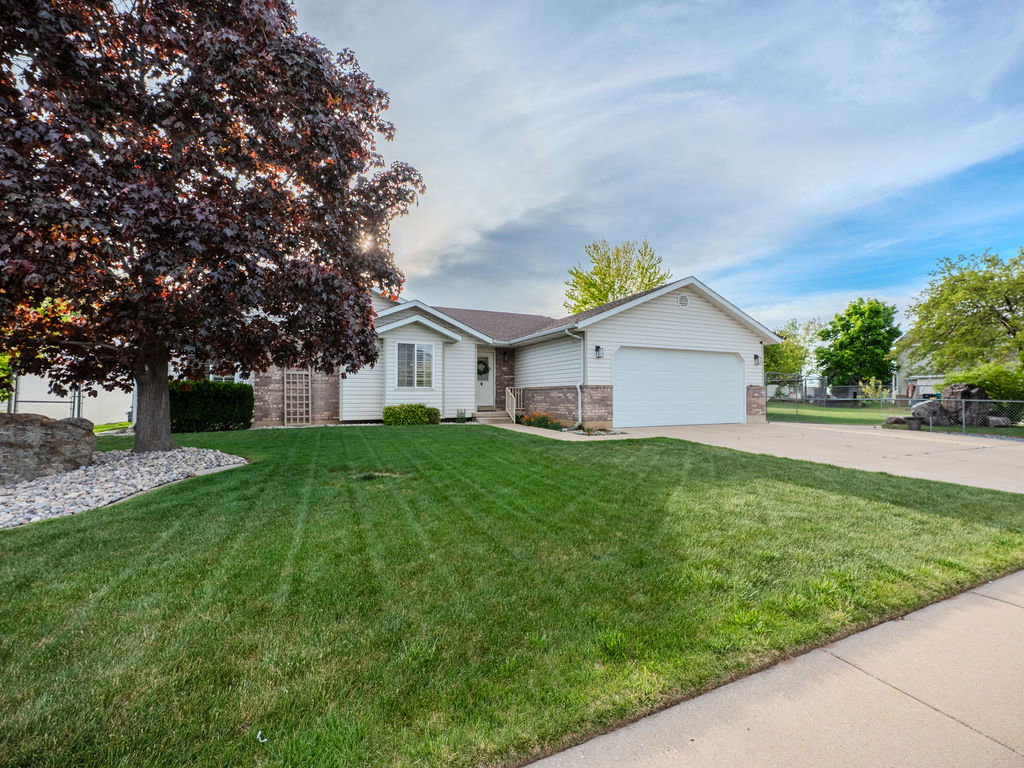 Ranch-style house with an attached garage, driveway, and brick siding