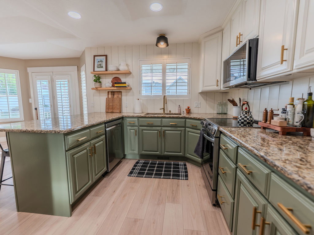 Two tone kitchen with a peninsula, stainless steel appliances, light wood-style floors, open shelves, and light stone counters