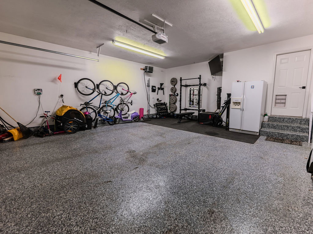 Garage featuring white refrigerator with ice dispenser and a garage door opener