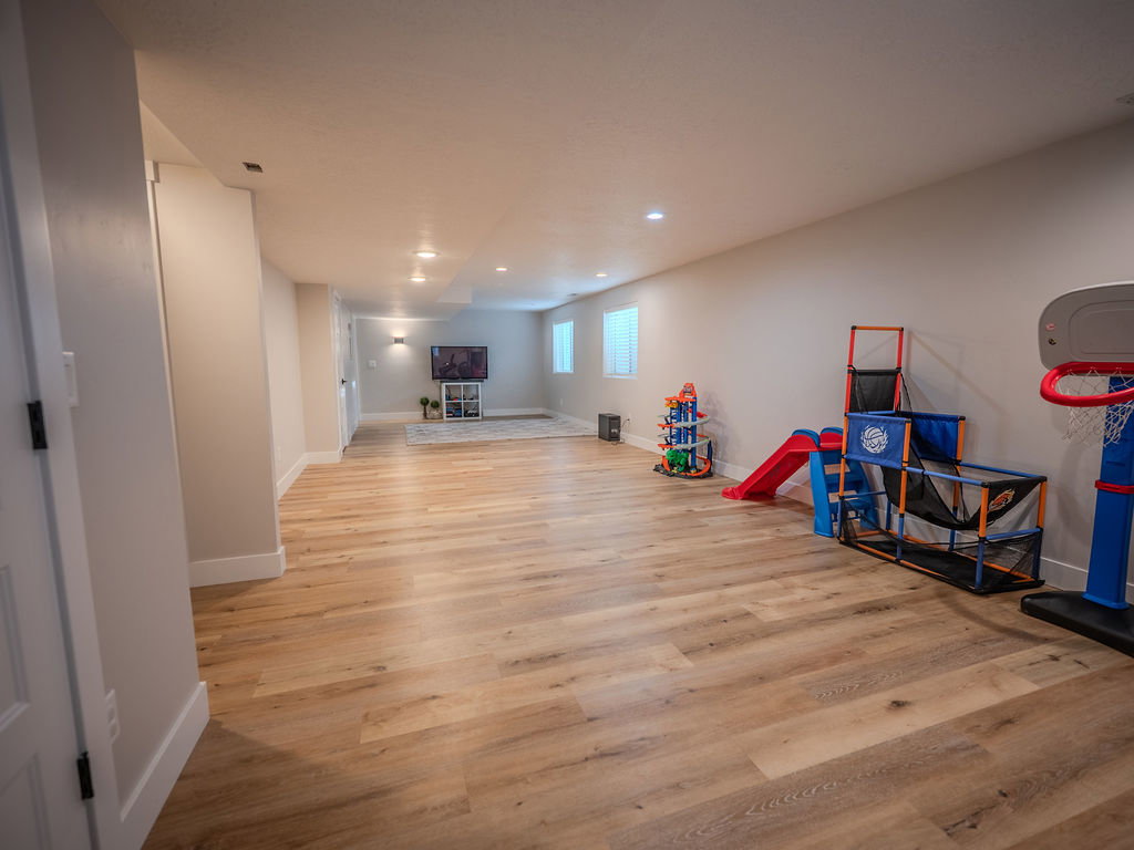 Recreation room with light wood-style floors and recessed lighting