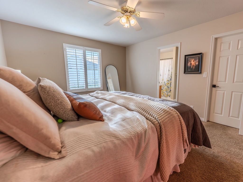 Carpeted bedroom featuring ceiling fan and ensuite bathroom