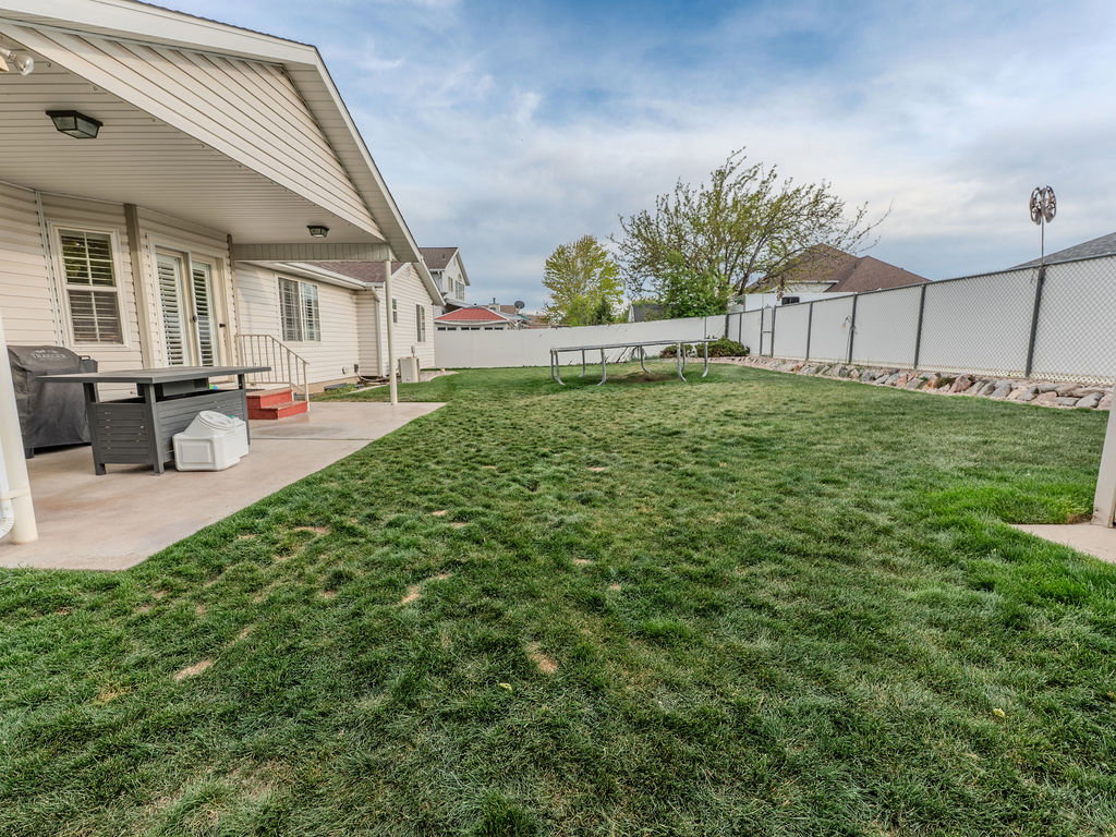 Fenced backyard featuring a patio area and a trampoline