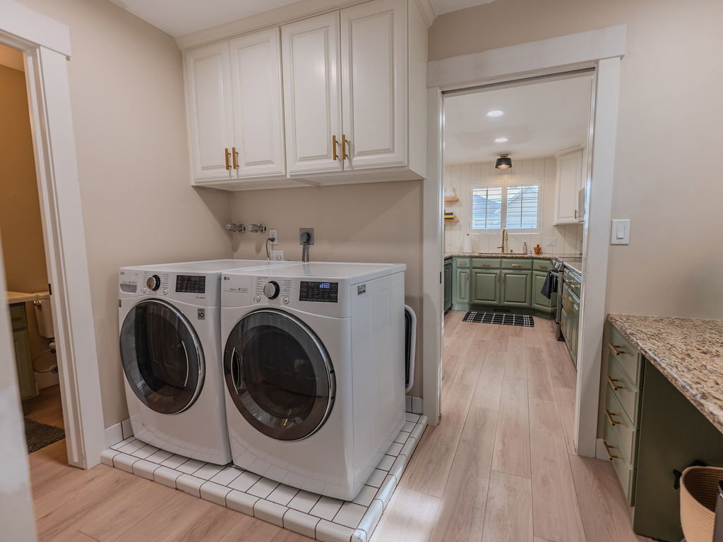 Laundry room with light wood-type flooring, washing machine and clothes dryer, cabinet space, and recessed lighting