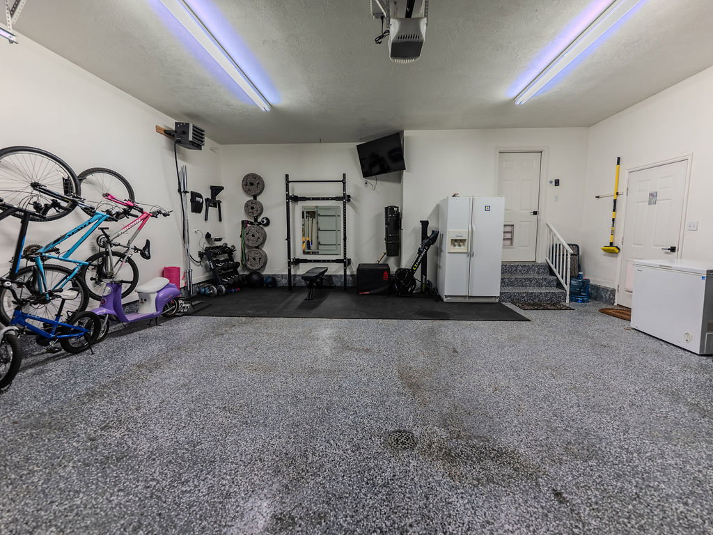 Garage with white fridge with ice dispenser, a garage door opener, and a heating unit