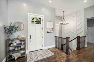 Foyer featuring dark wood finished floors and hanging lights