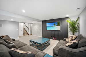 Carpeted living room featuring an accent wall and recessed lighting