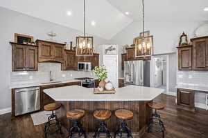 Gourmet kitchen offering custom staggered cabinetry, quartz countertops, stainless steel appliances, a gas range, a corner pantry, and an oversized island