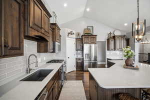 Gourmet kitchen offering custom staggered cabinetry, quartz countertops, stainless steel appliances, a gas range, a corner pantry, and an oversized island