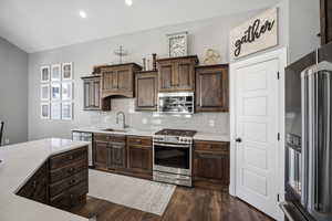 Gourmet kitchen offering custom staggered cabinetry, quartz countertops, stainless steel appliances, a gas range, a corner pantry, and an oversized island