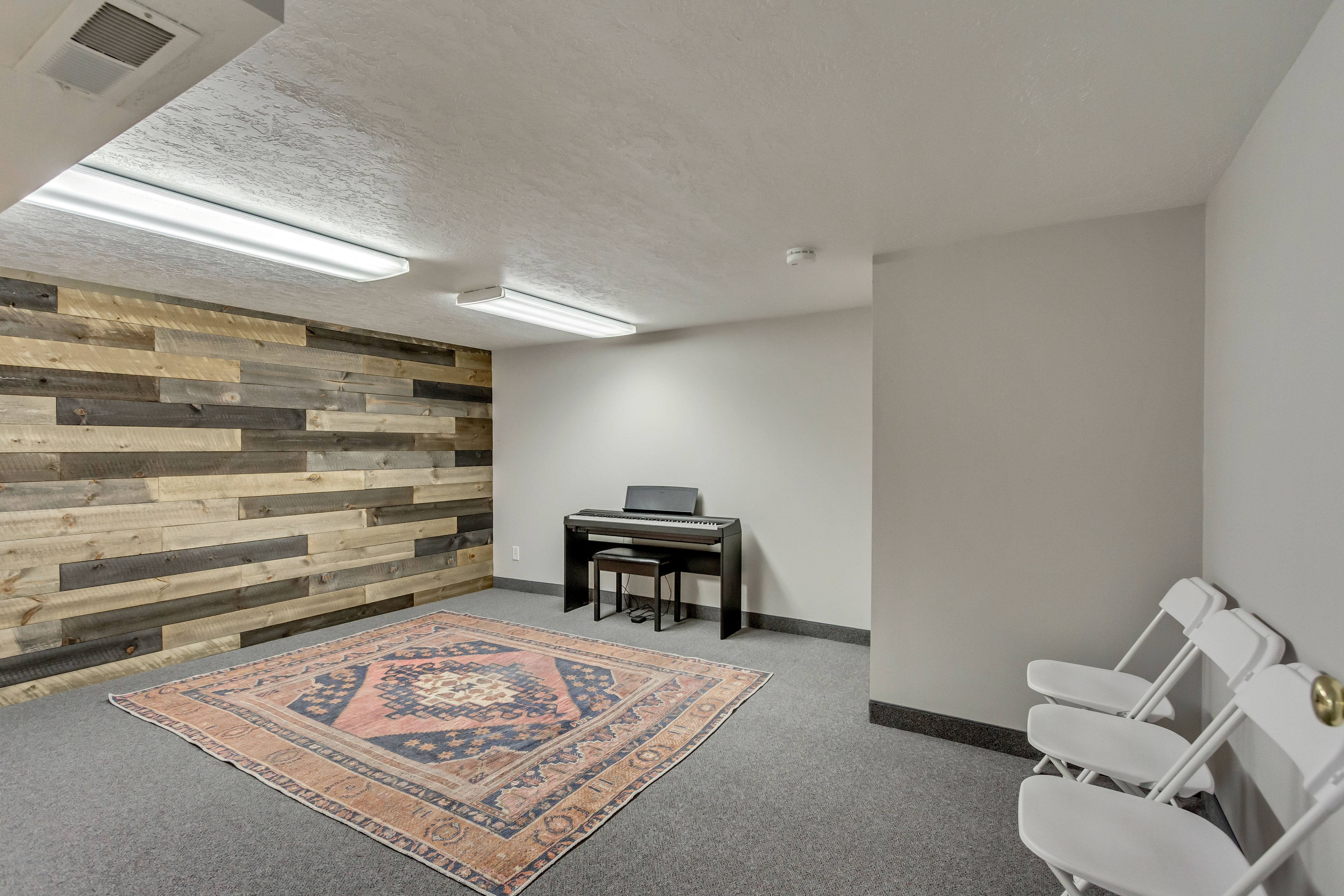 Sitting room with wooden walls, carpet floors, a textured ceiling, and an accent wall