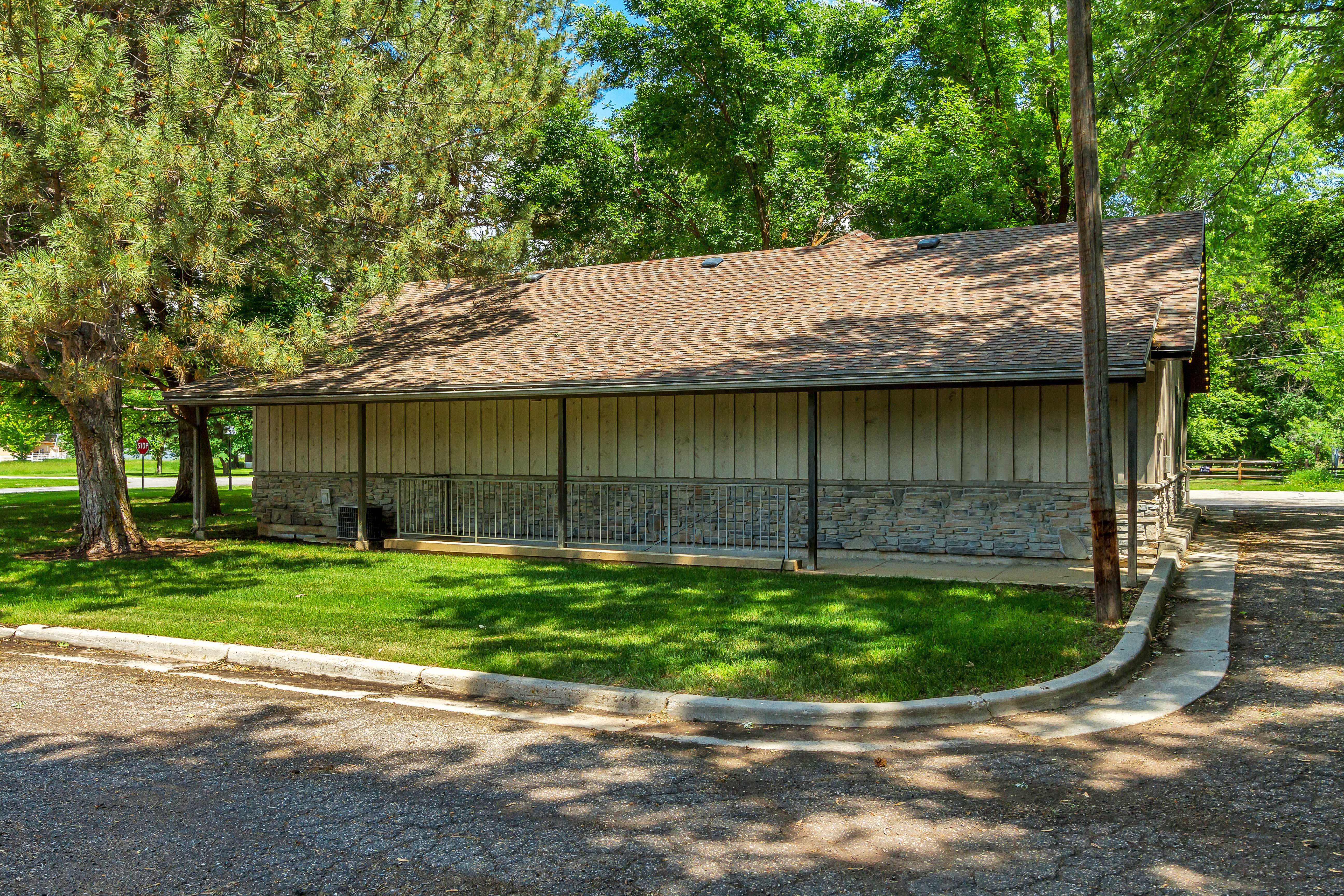 View of property exterior featuring roof with shingles, stone siding, a lawn, and board and batten siding