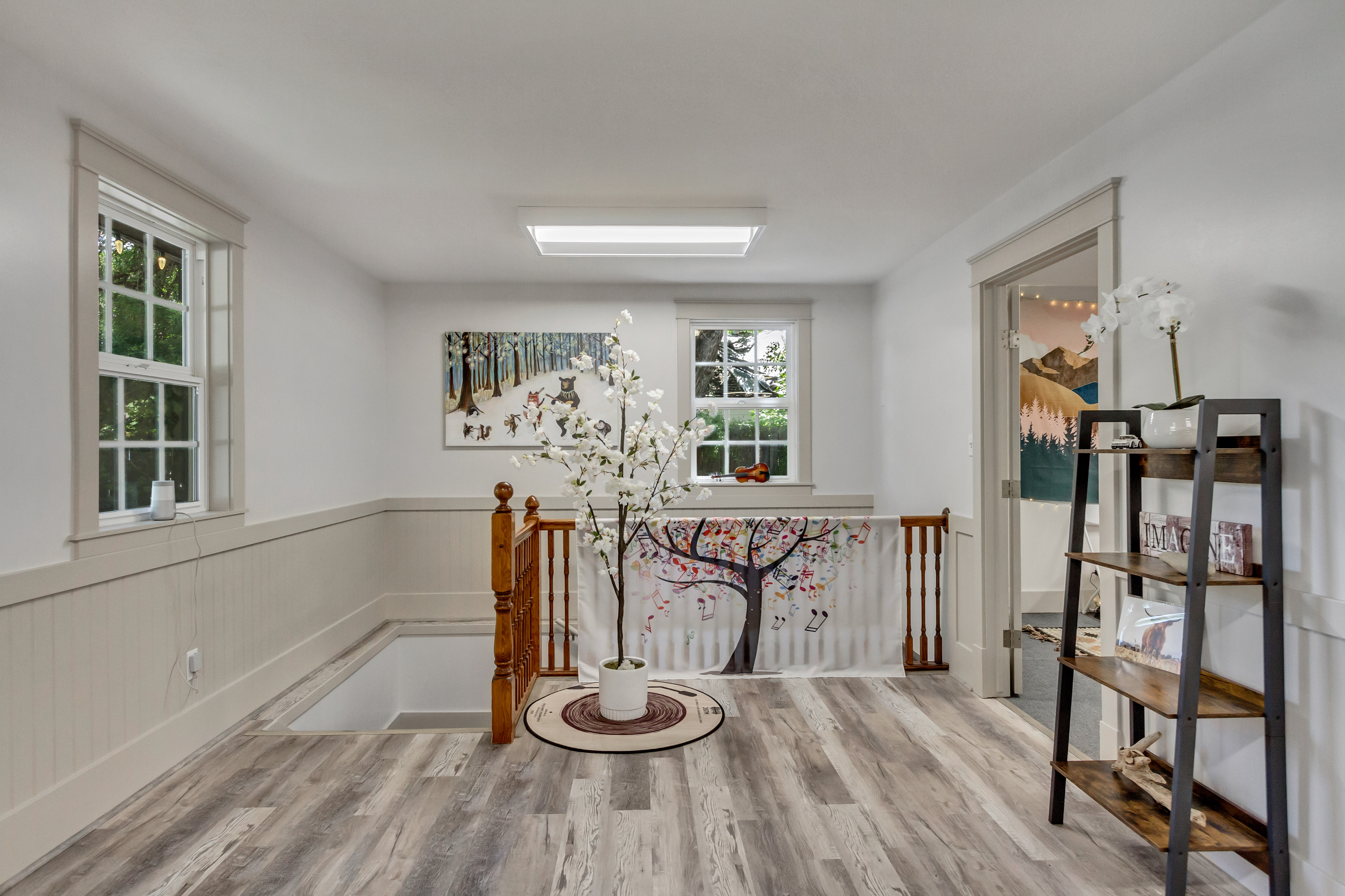 Corridor featuring an upstairs landing, a wainscoted wall, and light wood finished floors