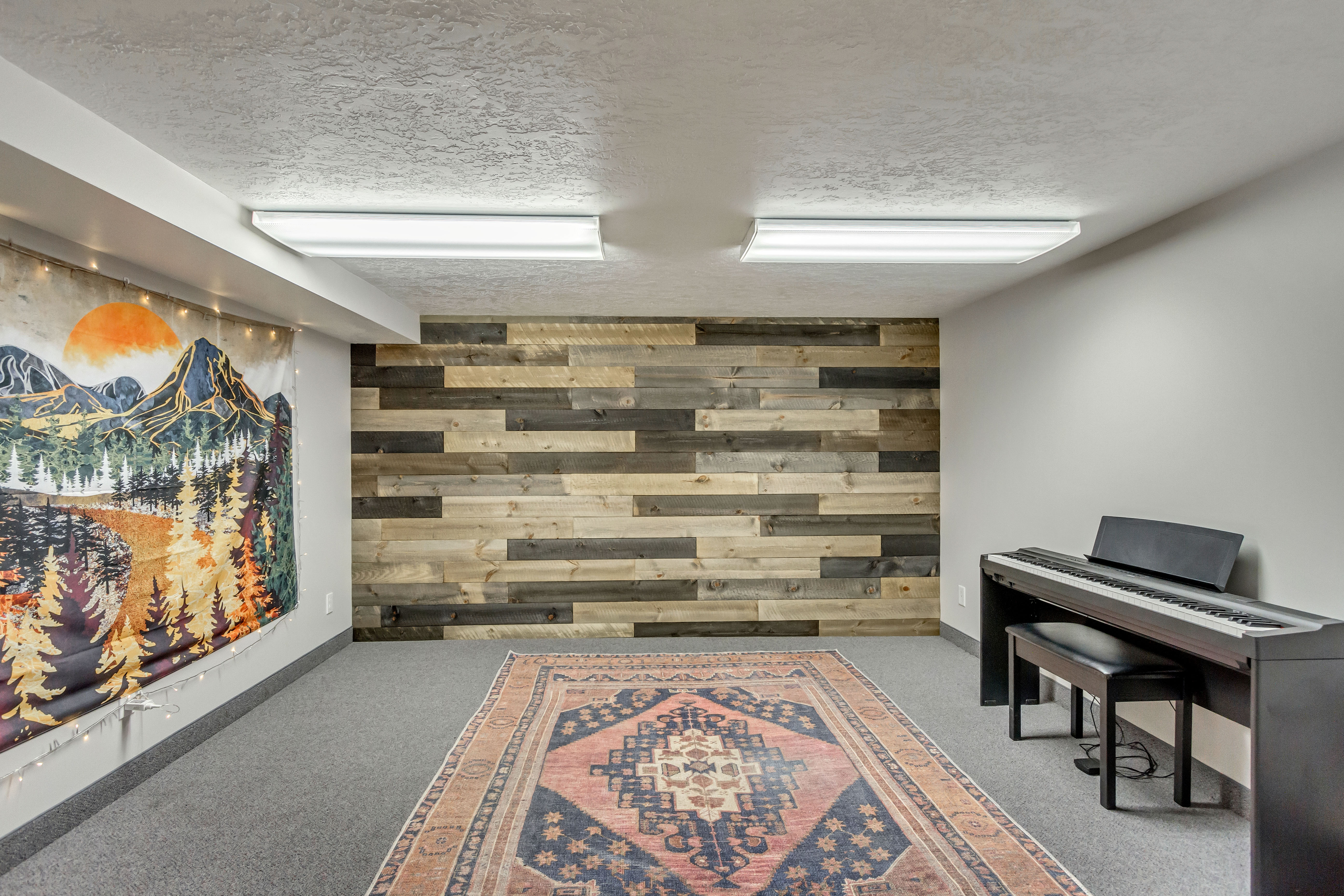 Living area featuring wooden walls, a textured ceiling, an accent wall, and light carpet