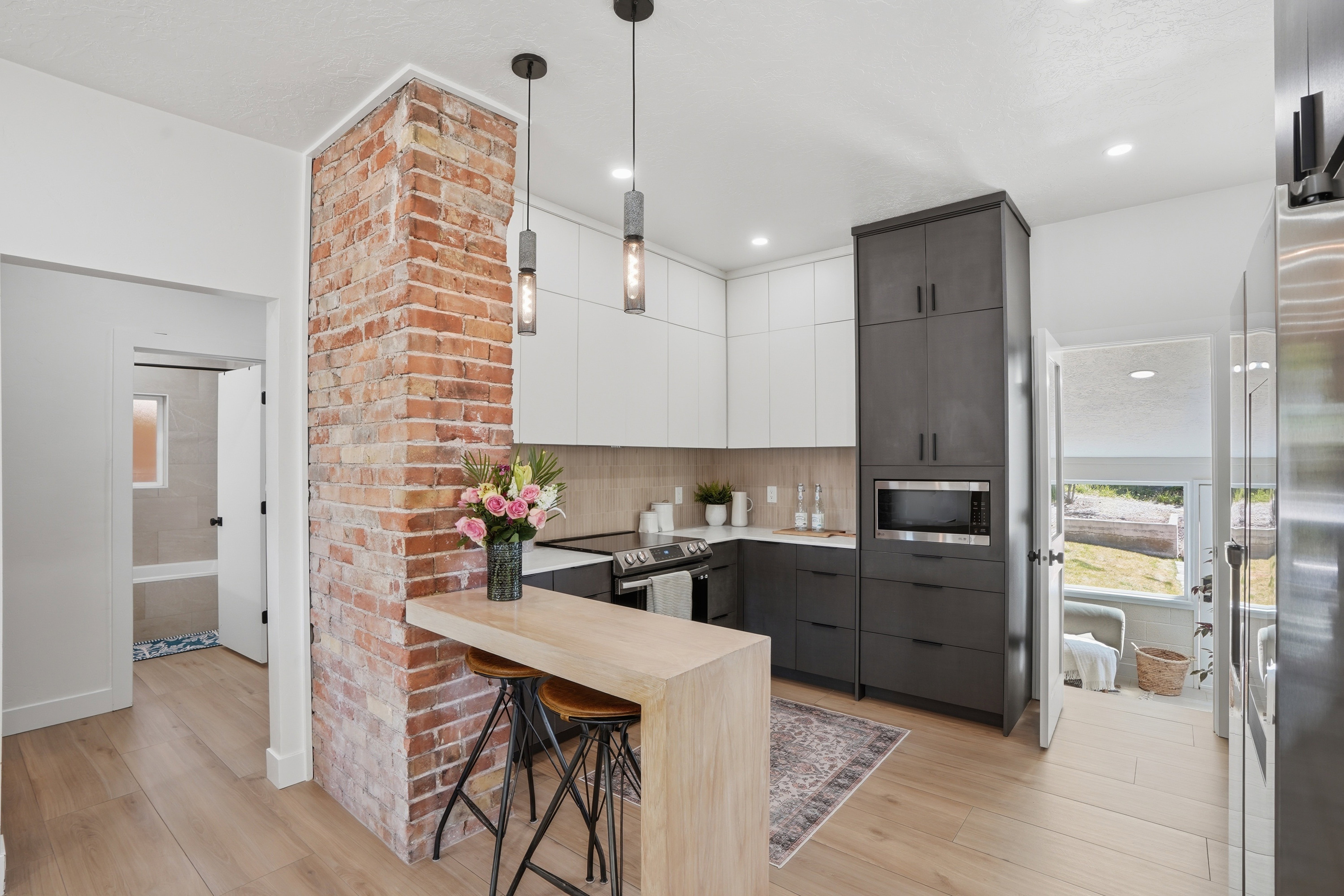 Kitchen featuring two tone color scheme, modern cabinets, pendant lighting, and a breakfast bar area