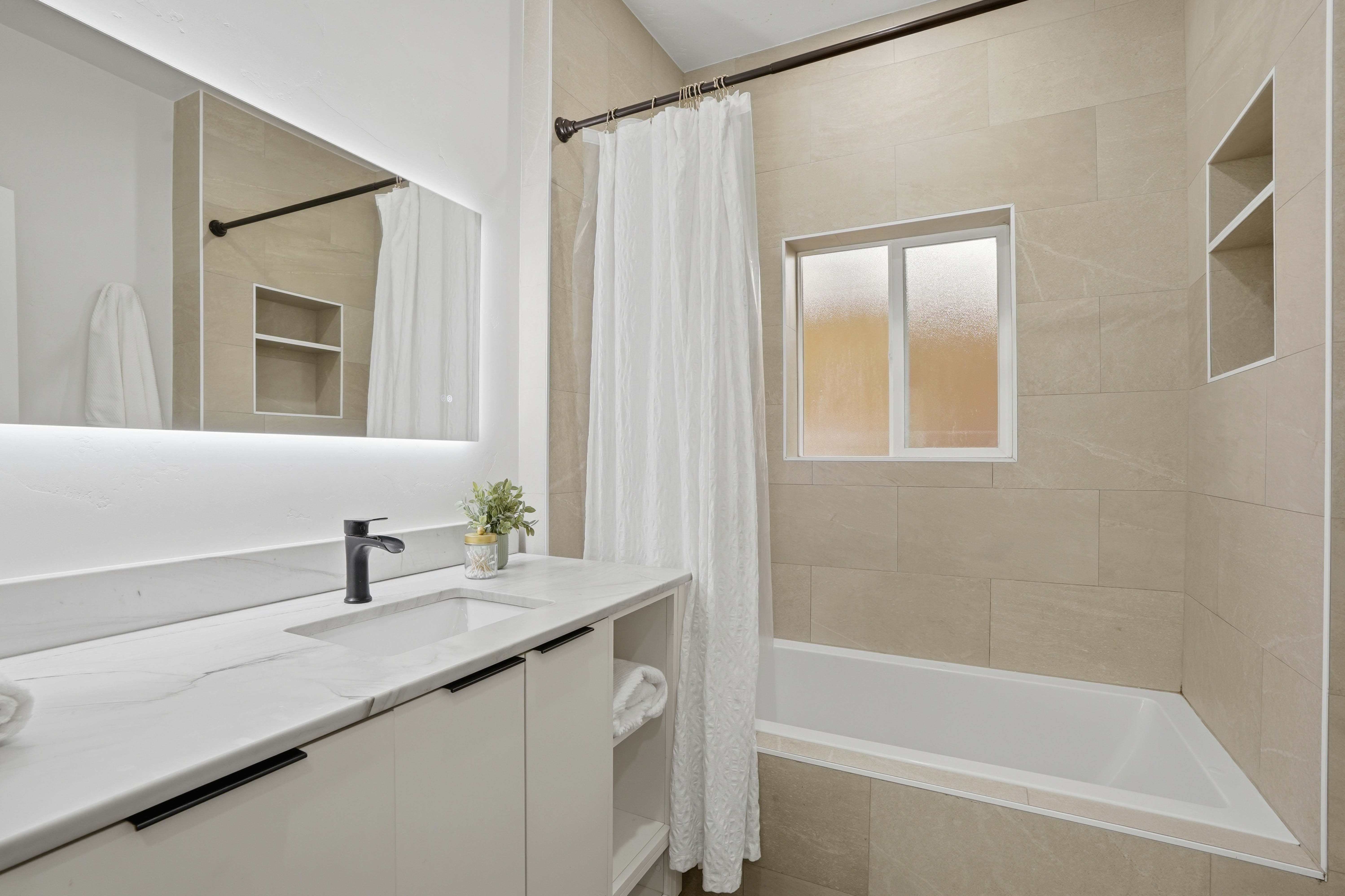 Full bath with vanity and tiled shower / bath combo with marble countertops