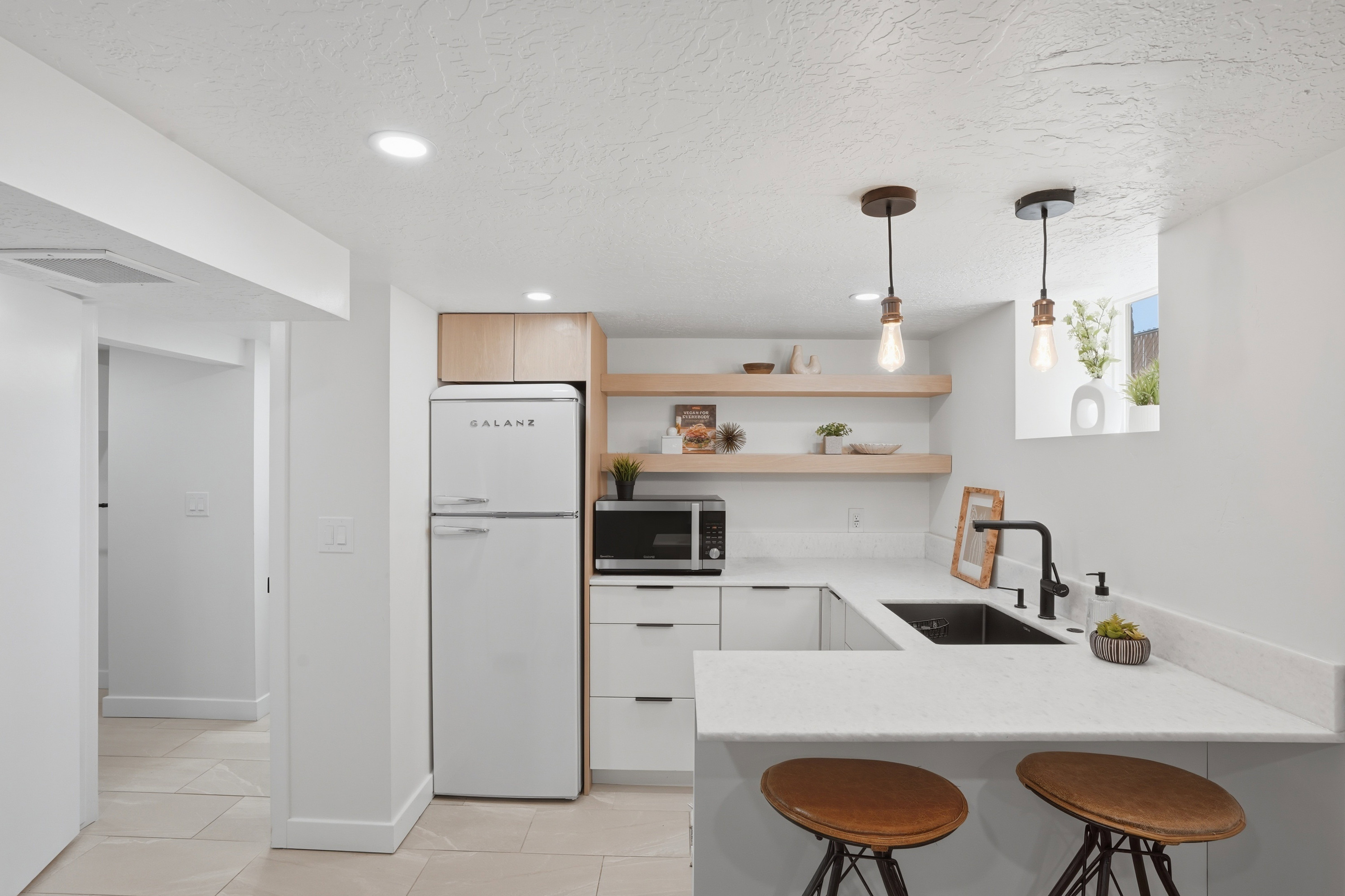 Kitchen with freestanding refrigerator, a peninsula kitchen breakfast bar, marble countertops and stainless steel microwave