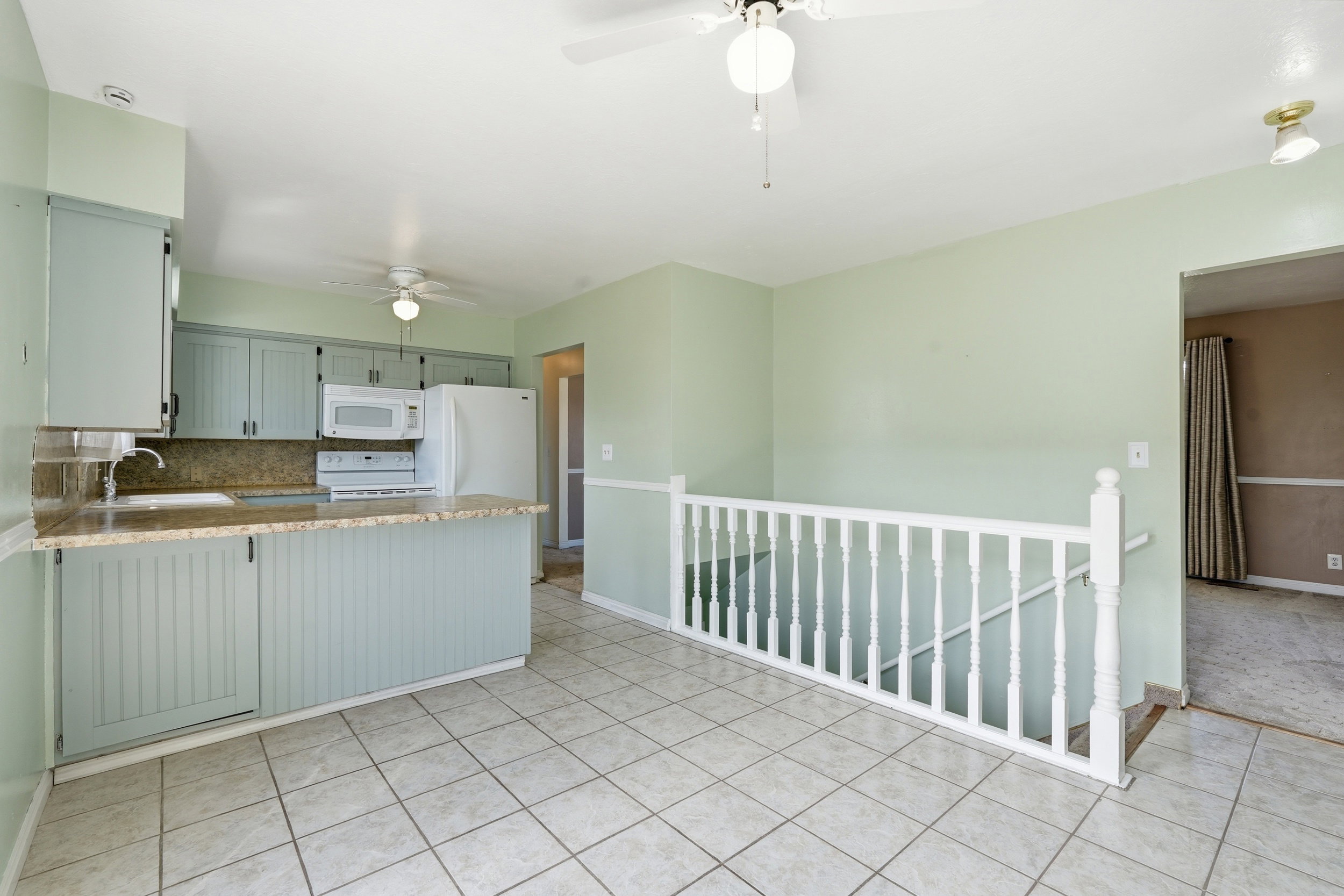 Kitchen with backsplash, white appliances, a ceiling fan, a peninsula, and light stone countertops