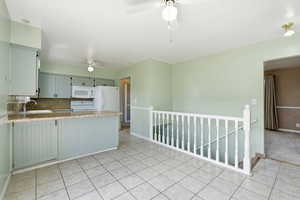 Kitchen with backsplash, white appliances, a ceiling fan, a peninsula, and light stone countertops