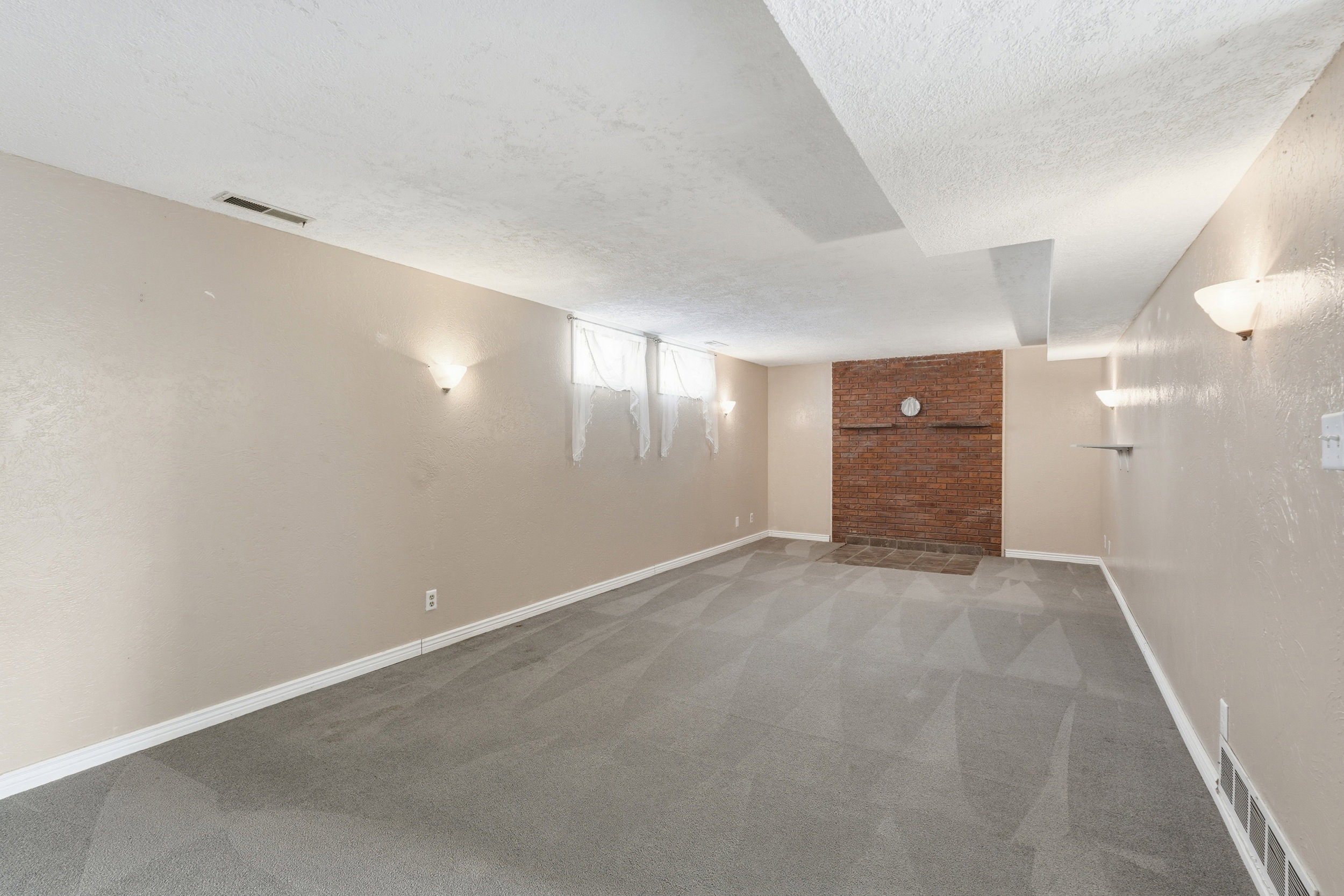 Below grade area with light carpet, a textured ceiling, and a textured wall
