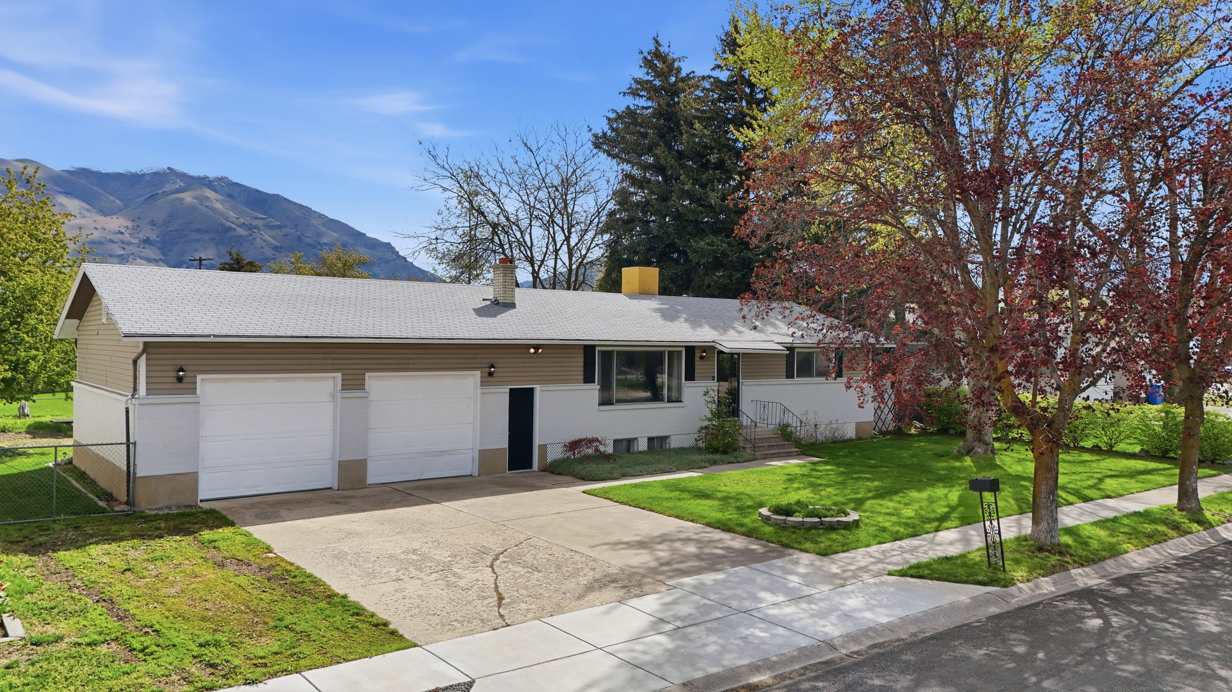 Ranch-style home with concrete driveway, a garage, a mountain view, and a chimney