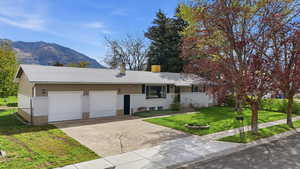 Ranch-style home with concrete driveway, a garage, a mountain view, and a chimney