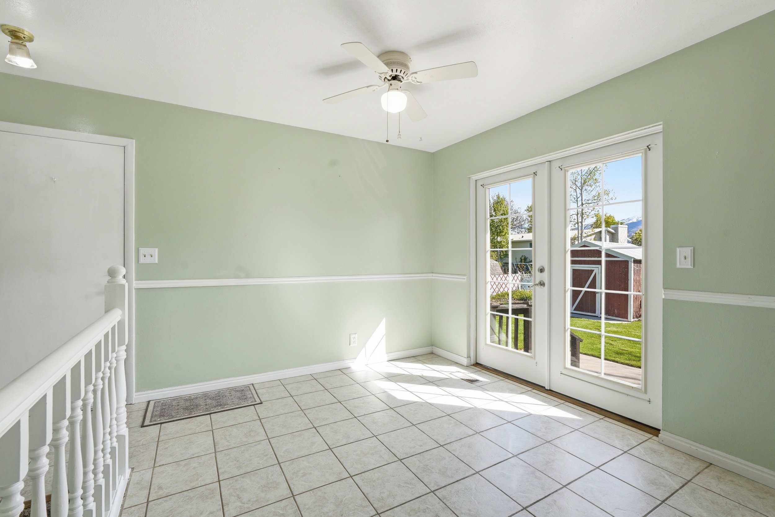 Empty room featuring french doors, ceiling fan, and light tile patterned flooring