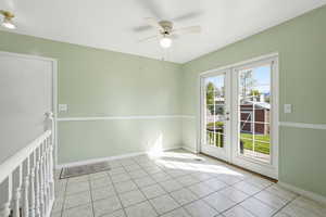 Empty room featuring french doors, ceiling fan, and light tile patterned flooring