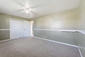 Unfurnished bedroom featuring carpet, a closet, and a ceiling fan