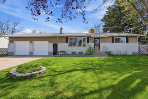 Ranch-style house with a chimney, a front lawn, concrete driveway, an attached garage, and brick siding