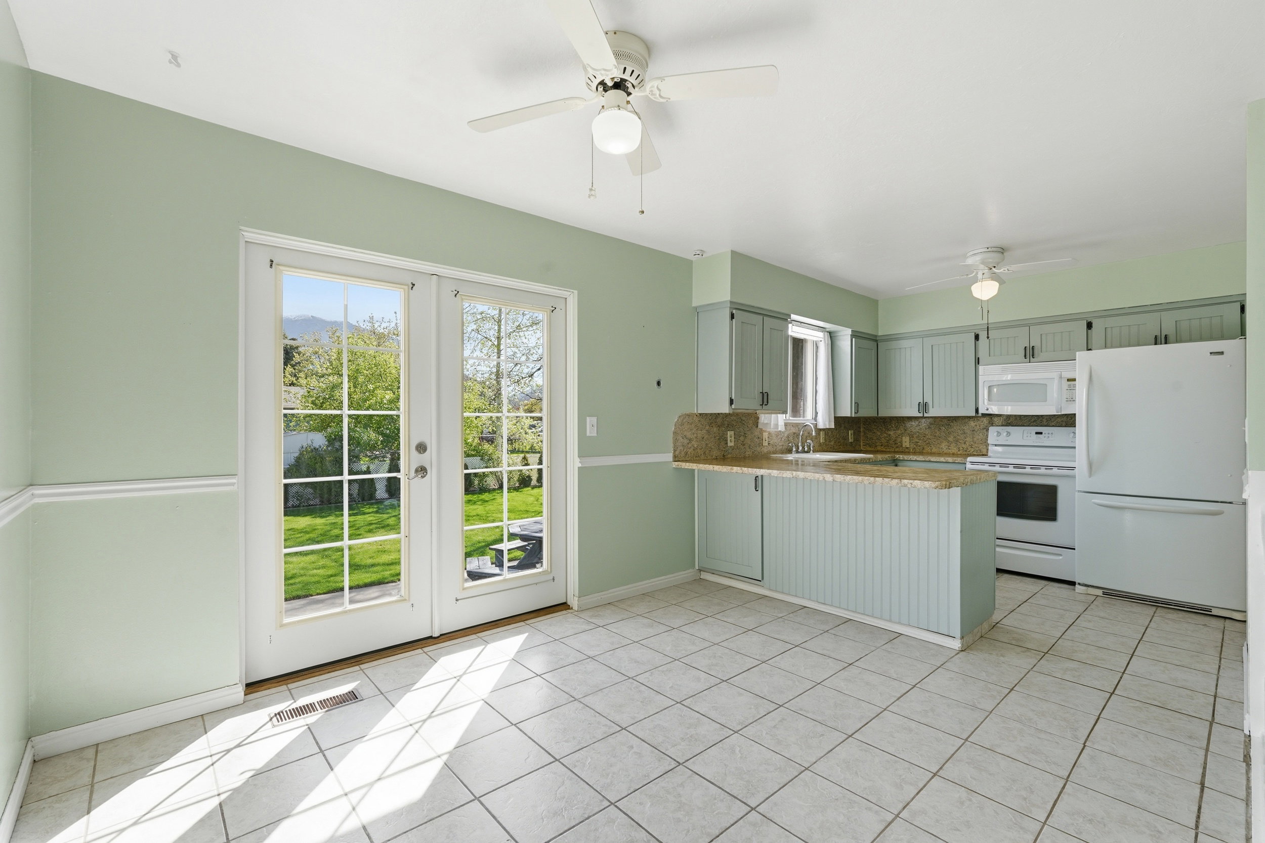 Kitchen with white appliances, a peninsula, decorative backsplash, a ceiling fan, and light countertops