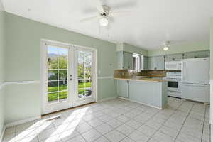 Kitchen with white appliances, a peninsula, decorative backsplash, a ceiling fan, and light countertops