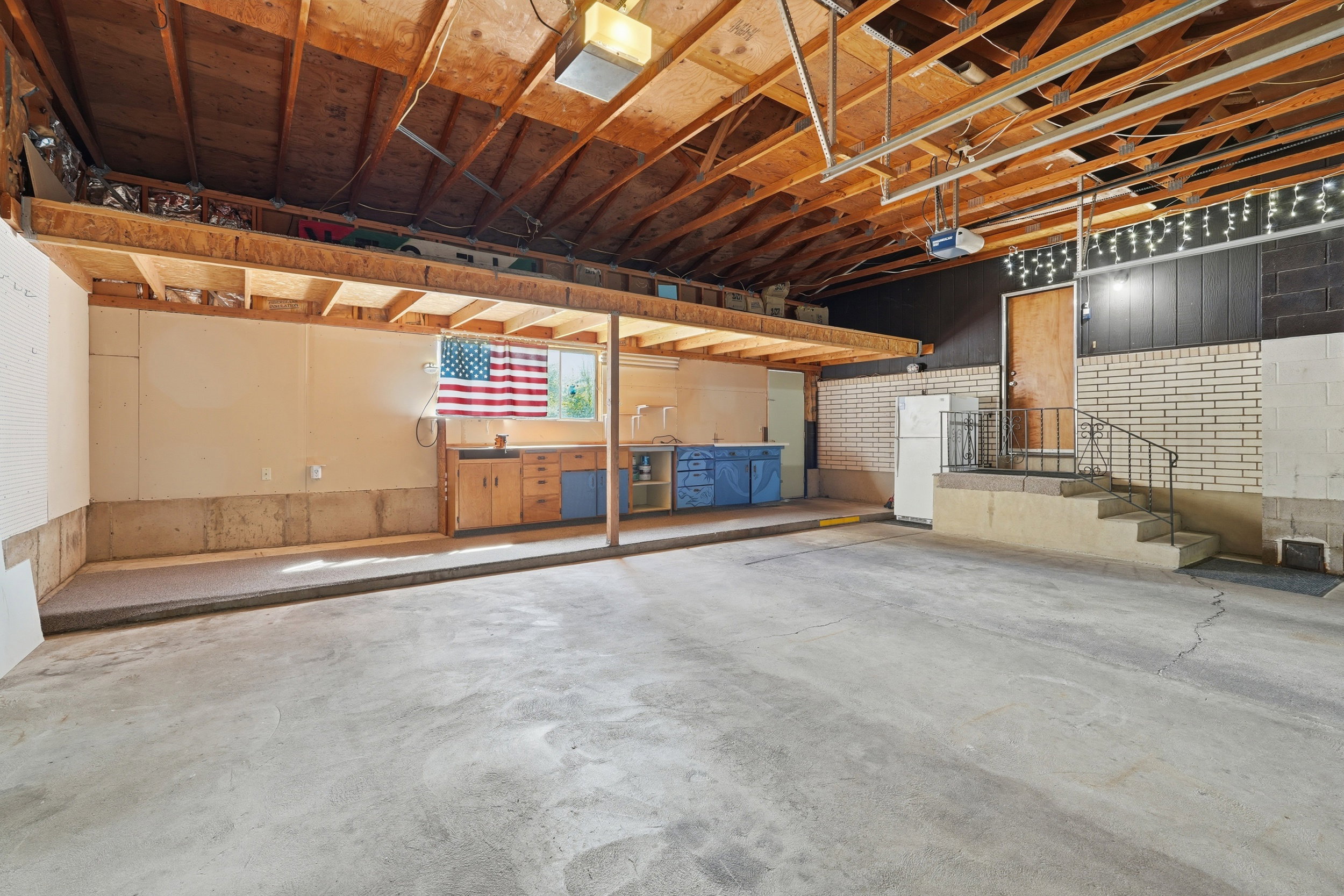 Garage featuring a garage door opener and freestanding refrigerator