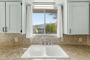 Kitchen with white cabinetry, backsplash, and light stone counters