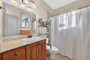 Bathroom featuring a wood-finish vanity with a light-toned countertop, oval undermount sink, and bronze-finish faucet