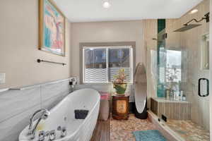 Freestanding soaking tub with integrated jets, complemented by a walk-in shower featuring a bench and rain showerhead