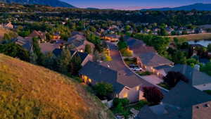 Expansive hillside property featuring established residential architecture, mature landscaping, paved roadways, and a distant water feature