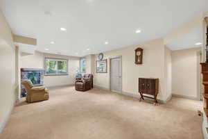 Spacious lower-level room featuring recessed lighting, plush carpeting, and a stone-faced fireplace
