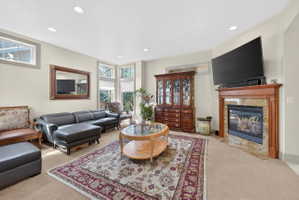 Carpeted living room with plenty of natural light, a premium fireplace, and recessed lighting
